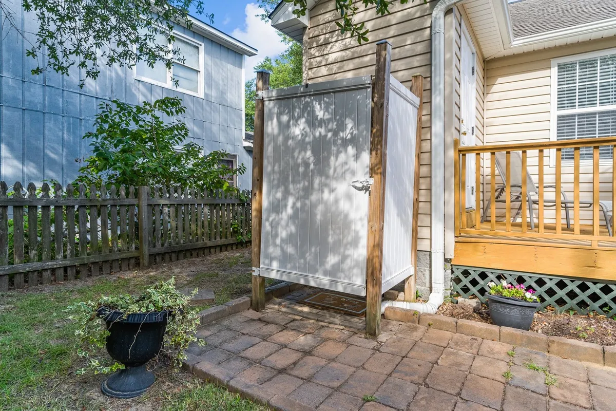 This image captures a tranquil backyard featuring a tall privacy fence, a neat deck, a storage shed, and lush landscaping. The fully fenced perimeter is clearly visible, creating a sense of safety and enclosure. The inviting deck overlooks the green garden, suggesting a relaxing outdoor space for both people and pets.