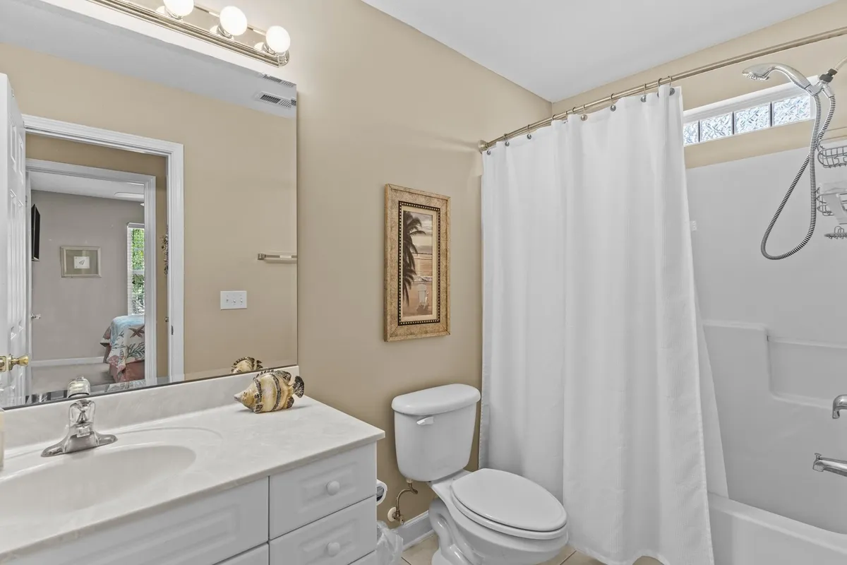A stylish bathroom with a vanity sink, mirror, framed artwork, and a partial view of the shower area. The space is clean, bright, and designed for personal comfort and relaxation.