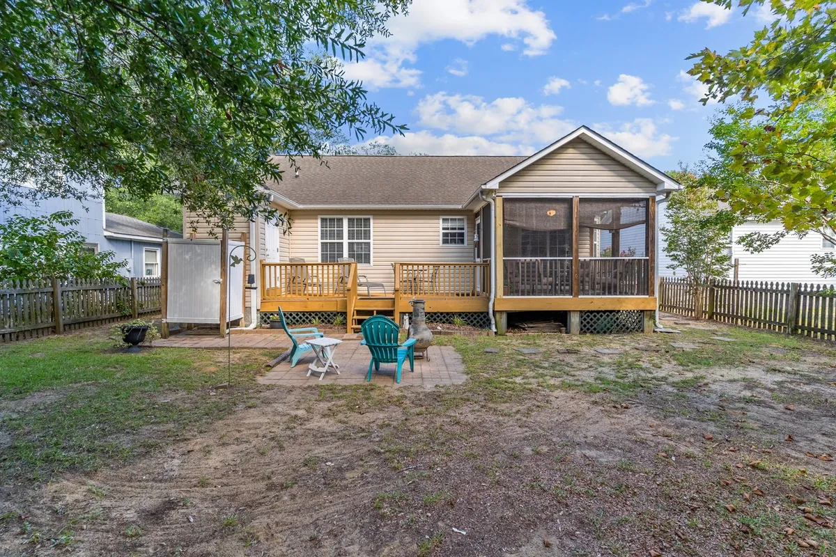 This image showcases a screened porch leading onto a deck with outdoor seating, all overlooking a fenced backyard. The seating area on the deck and visible fencing encapsulate the inviting, family- and pet-friendly atmosphere described in the section.