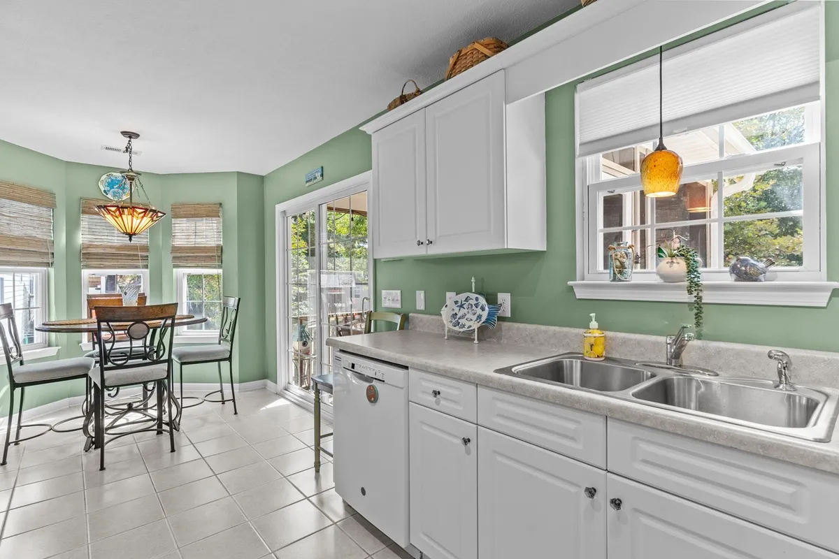 A spacious, welcoming kitchen and dining area featuring a kitchen island, dining table, large windows, and a decorative pendant light. The scene captures an open-concept flow ideal for family meals, cooking together, and casual entertaining.
